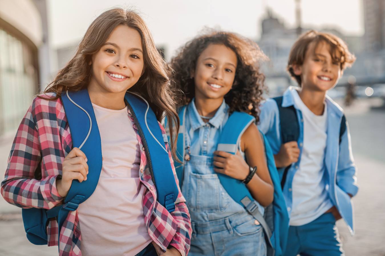 Three children smiling with backpacks on