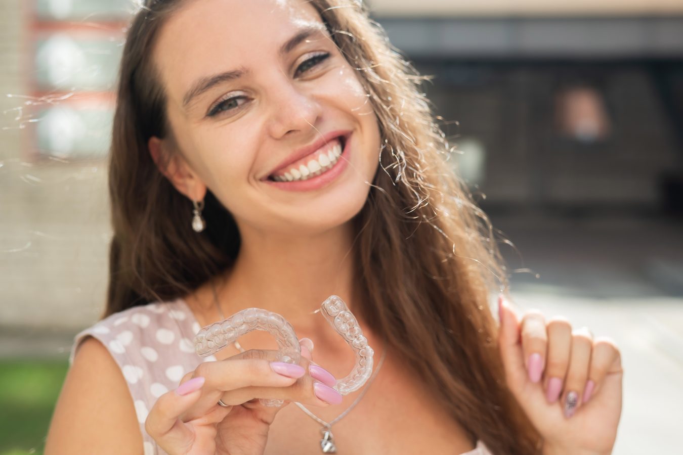 Woman smiling and holding clear aligners