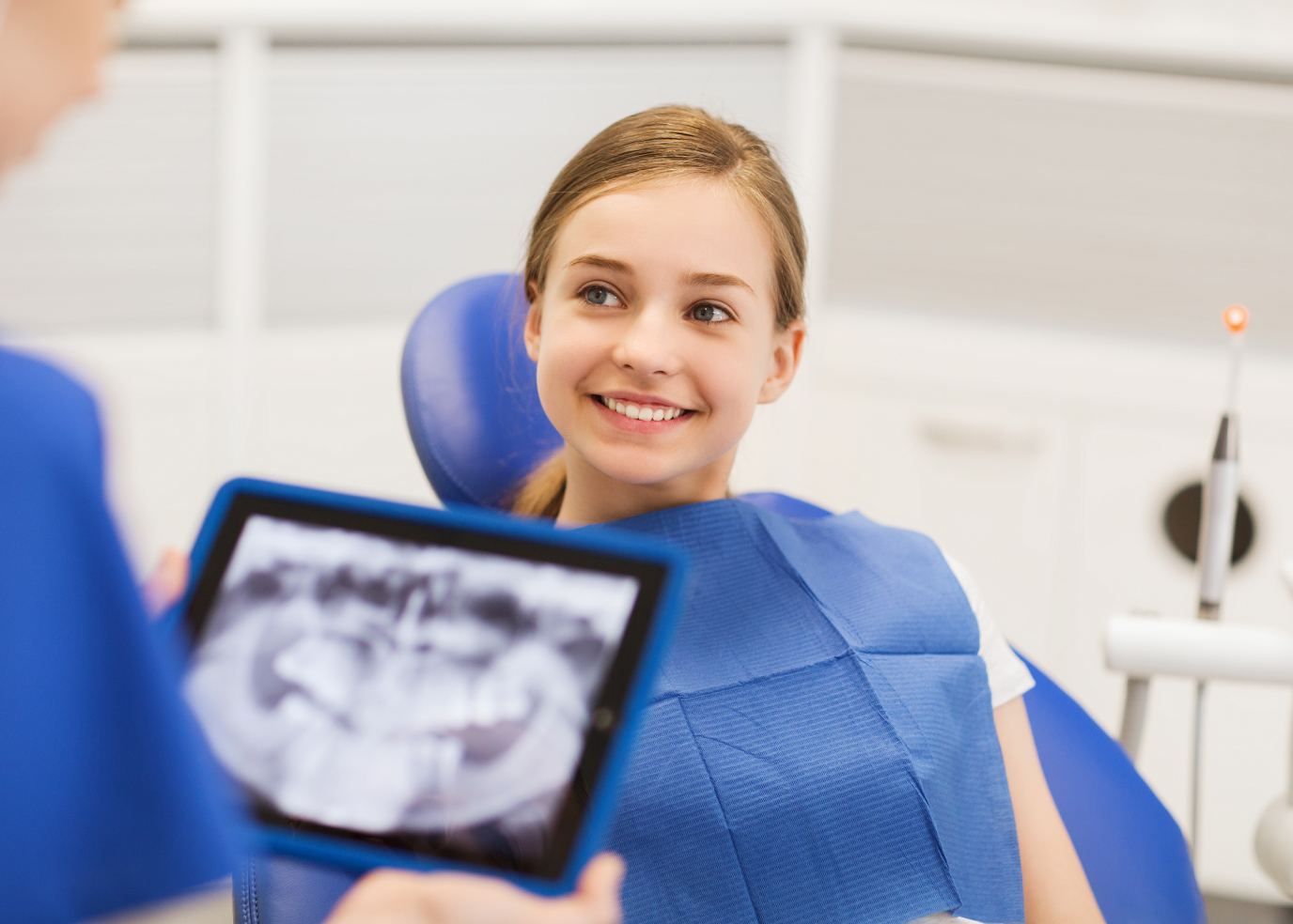 A teenage girl smiling while sitting in an exam chair